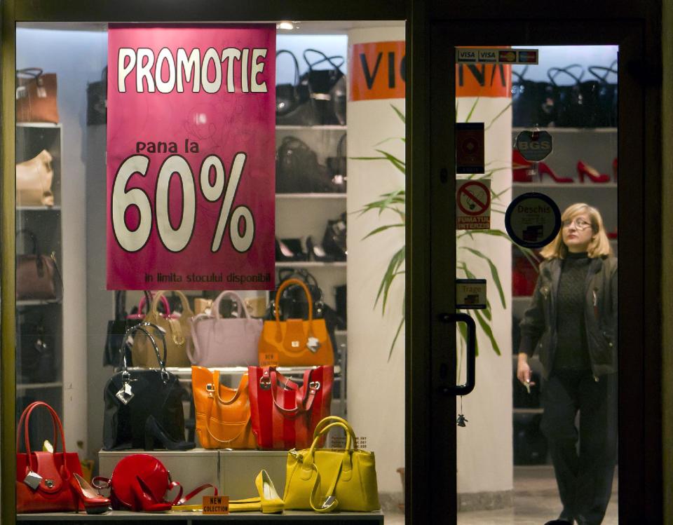 A vendor prepares to close shop downtown Bucharest, Romania, as a window poster advertises price reductions, Friday, March 16, 2012. The coldest winter in living memory is over, and spring has arrived in Prague, Belgrade and Bucharest, but from the look in shop windows, with massive reductions and bargains galore, you'd think we were still in the winter sales. (AP Photo/Vadim Ghirda)