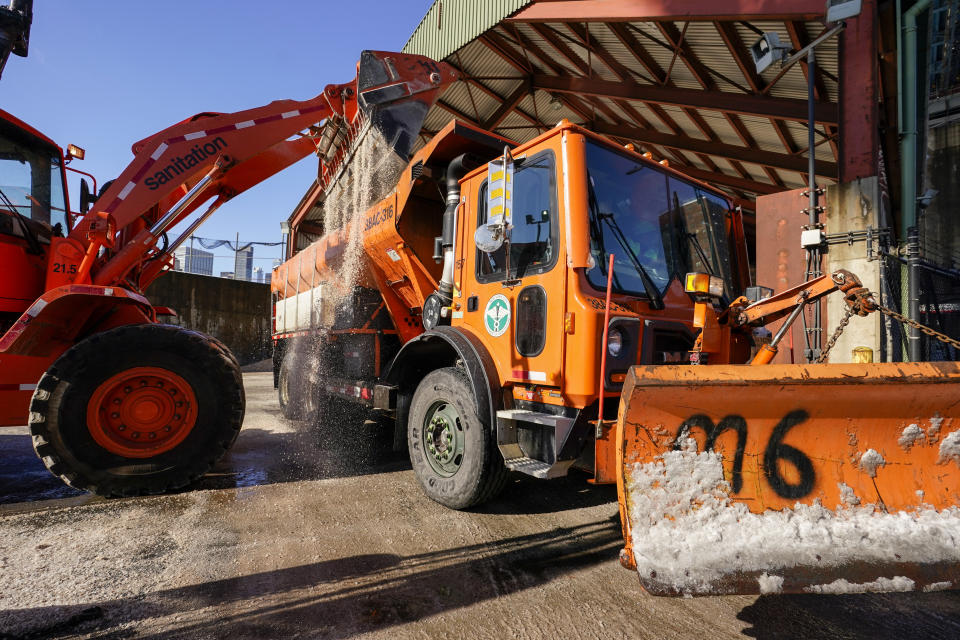 New York City Sanitation Department workers use a front-end loader to to fill a salt spreader at one of the Department's salt sheds in lower Manhattan, Friday, Jan. 7, 2022, in New York. A winter storm that has already left areas of the south with more than 6 inches of snow moved into the northeast during the morning commute and prompted many school districts to close for the day. (AP Photo/Mary Altaffer)