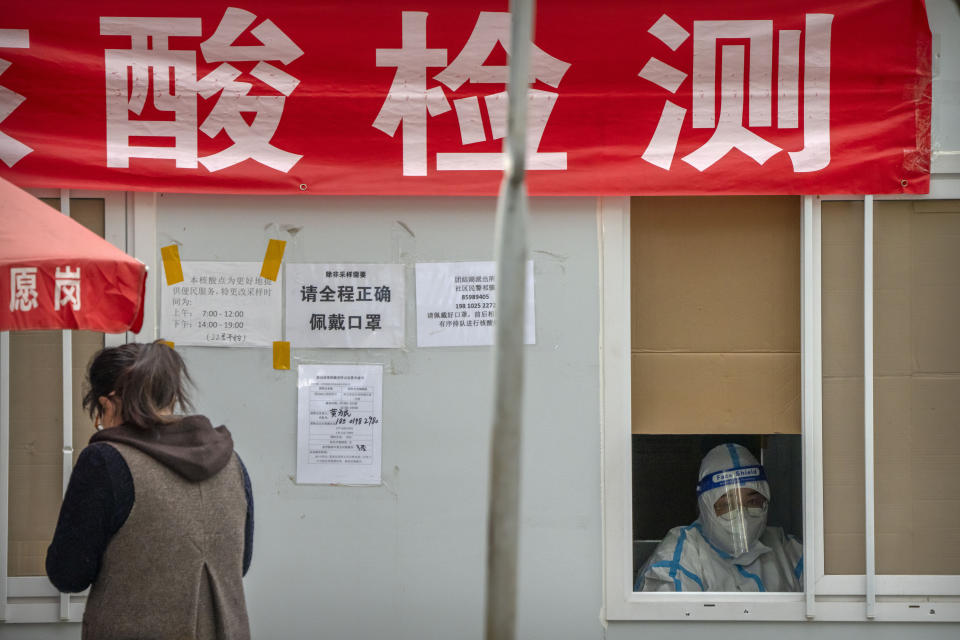 A worker wearing a protective suit waits to administer a COVID-19 test at a coronavirus testing site in Beijing, Wednesday, Oct. 5, 2022. (AP Photo/Mark Schiefelbein)