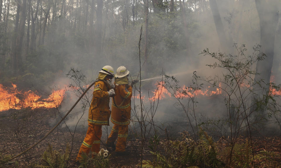 A firefighter hoses to control flames near houses at Bilpin, 75 kilometers (47 miles) west of Sydney, Australia, Tuesday, Oct. 22, 2013. (AP Photo/Rob Griffith)