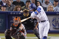 Los Angeles Dodgers' Chris Taylor, right, hits a two-run home run while San Francisco Giants catcher Buster Posey, left, and home plate umpire Dan Iassogna watch during the sixth inning of a baseball game Tuesday, July 20, 2021, in Los Angeles. (AP Photo/Mark J. Terrill)