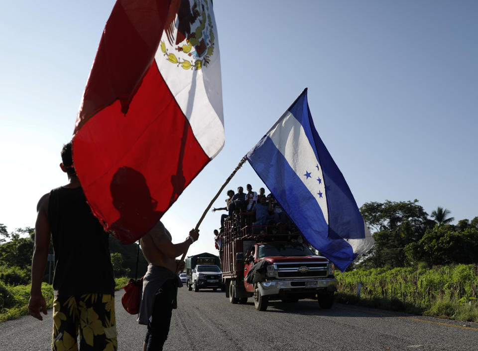 Honduran migrants walking north wave the flags of Honduras and Mexico to passing trucks carrying migrants, as a thousands strong caravan heads north trying to reach the U.S., still over 1000 miles away, near Mapastepec, Mexico, Thursday, Oct. 25, 2018. Some Hondurans in the caravan have said they are fleeing political reprisals from conservative President Juan Orlando Hernandez’s government, though most commonly one hears stories about the dangers of living among hyper-violent gangs. (AP Photo/Rebecca Blackwell)