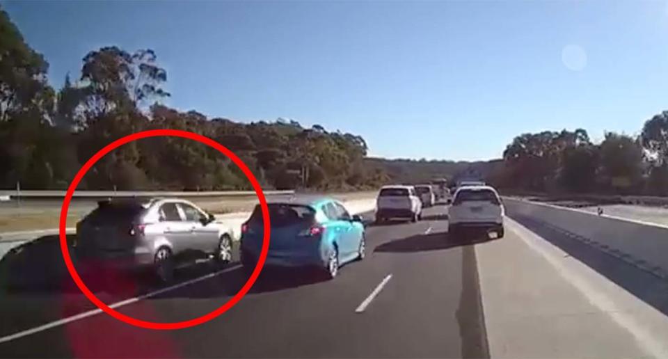 A silver hatchback is seen using an emergency stopping lane to overtake cars on a highway near Gosford on the Central Coast.