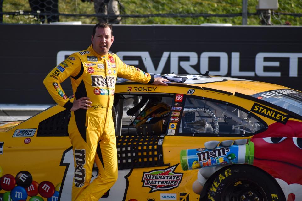 Kyle Busch poses with his No. 18 M&M's Toyota after winning the Explore the Pocono Mountains 350 Cup Series race at Pocono Raceway in Long Pond on Sunday, June 27, 2021.