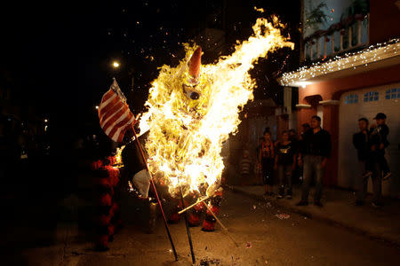 People look at a pinata representing U.S. President-elect Donald Trump as a devil burning during the traditional Burning of the Devil festival, ahead of Christmas in Guatemala City, Guatemala December 7, 2016. REUTERS/Luis Echeverria