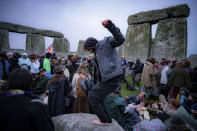 People inside the stone circle during Summer Solstice at Stonehenge, where some people jumped over the fence to enter the stone-circle to watch the sun rise at dawn of the longest day of the year in the UK, in Amesbury, England, Monday June 21, 2021. The prehistoric monument of ancient stones have been officially closed for the celebrations due to the coronavirus lockdown, but groups of people ignored the lockdown to mark the Solstice, watched by low key security. (Ben Birchall/PA via AP)