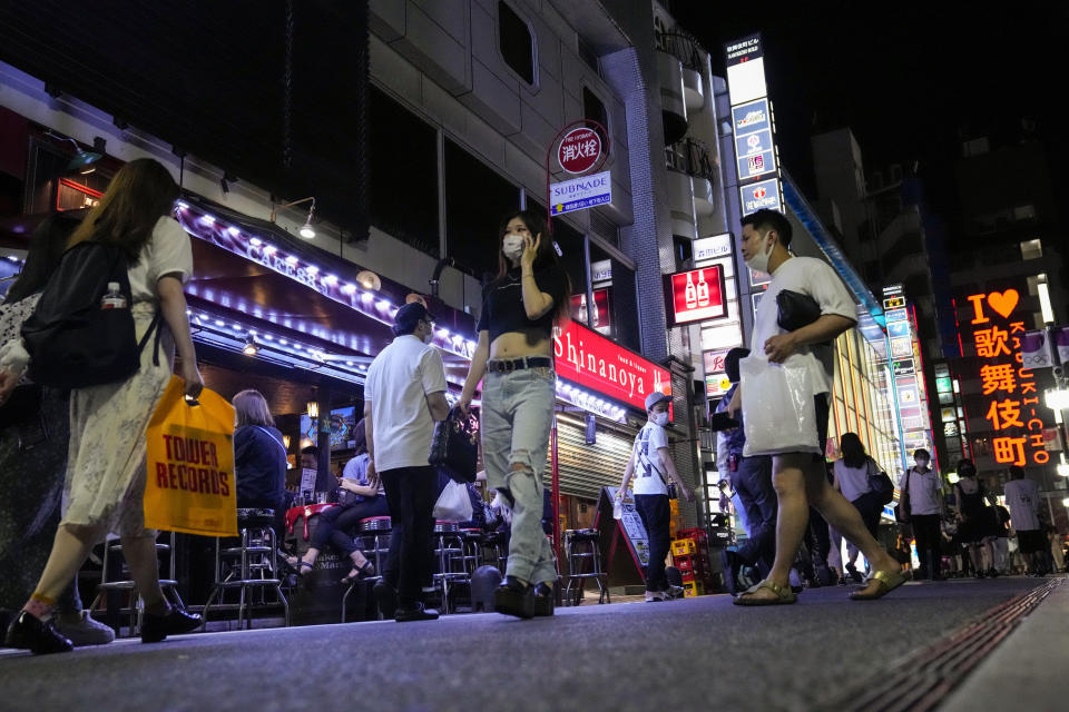 People walk around and gather at a bar after government imposed 8 p.m. closing time for restaurants and bars under Tokyo's fourth state of emergency Saturday, July 17, 2021, in Tokyo. The latest state of emergency has asked restaurants and bars to close by 8 p.m., if not entirely. This has pushed people to drink outside, although many bars remain open and bustling with customers who are defying the rules and expressing frustration and indifference. (AP Photo/Kiichiro Sato)