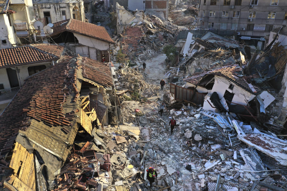 FILE - People walk on the debris of heritage houses that destroyed during the devastated earthquake, in the old city of Antakya, southern Turkey, Monday, Feb. 13, 2023. Antakya, known as Antioch in ancient times, has been destroyed many times by earthquakes. It was destroyed yet again by an earthquake Feb. 6, and residents are wondering if its ancient glories will ever come back. (AP Photo/Hussein Malla, File)