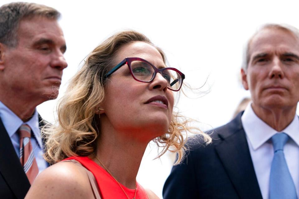 Sen. Kyrsten Sinema, D-Ariz., center, Sen. Mark Warner, D-Va., left, and Sen. Rob Portman, R-Ohio, speak with reporters upon arriving at the Capitol after a meeting with President Joe Biden at the White House in Washington, Thursday, June 24, 2021. A bipartisan group of lawmakers have negotiated a plan to pay for an estimated $1 trillion compromise plan. (AP Photo/Alex Brandon)