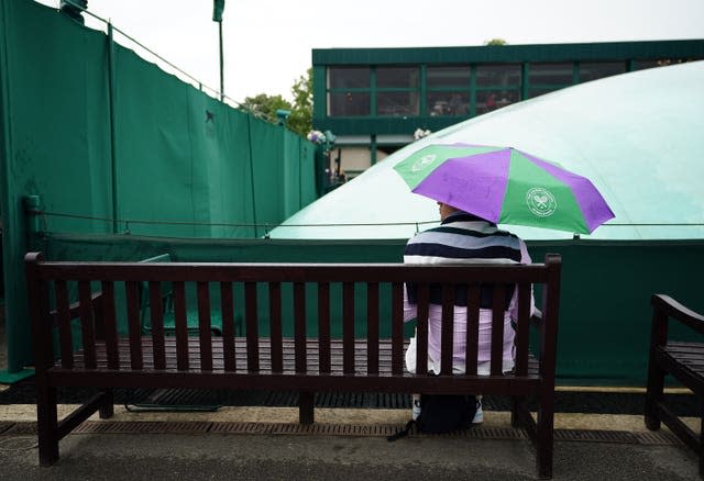 Spectator shelters from rain at Wimbledon