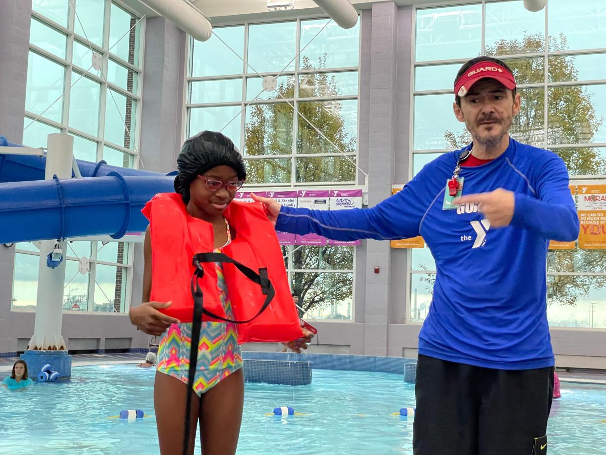 Malani Smith demonstrates how to wear a life jacket with YMCA lifeguard and water safety instructor Kevin Toole on Nov. 17, 2023.