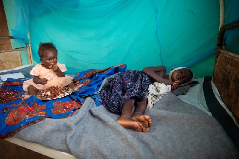 Bonheur Ketadumbea, who has contracted measles, looks out of the door of the family kitchen as his mother, Manzenge Ekabe, makes dinner in the outskirts of the town of Boso-Manzi in Mongala province