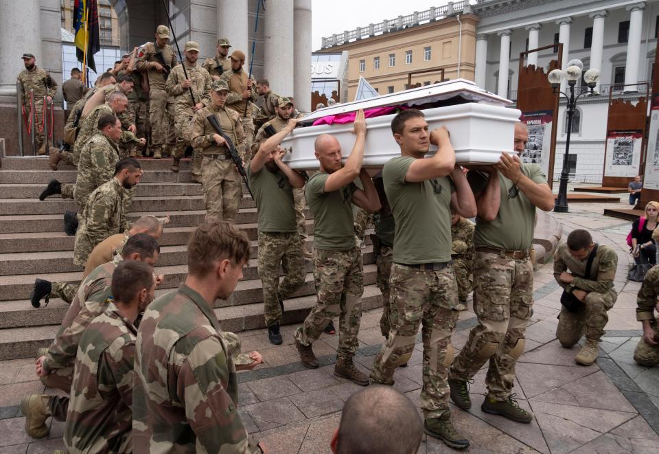 Ukrainian servicemen kneel as soldiers transport a coffin during the funeral of officers Andriy Zhovanyk and Yuri Kovalenko, killed in a battle against the Russian troops, in central Independence square in Kyiv, Ukraine.