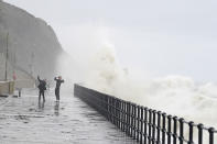 People run away from crashing waves at the promenade in Folkestone, England, Thursday, Nov, 2, 2023, as Storm Ciaran brings high winds and heavy rain along the south coast of England. (Gareth Fuller/PA via AP)