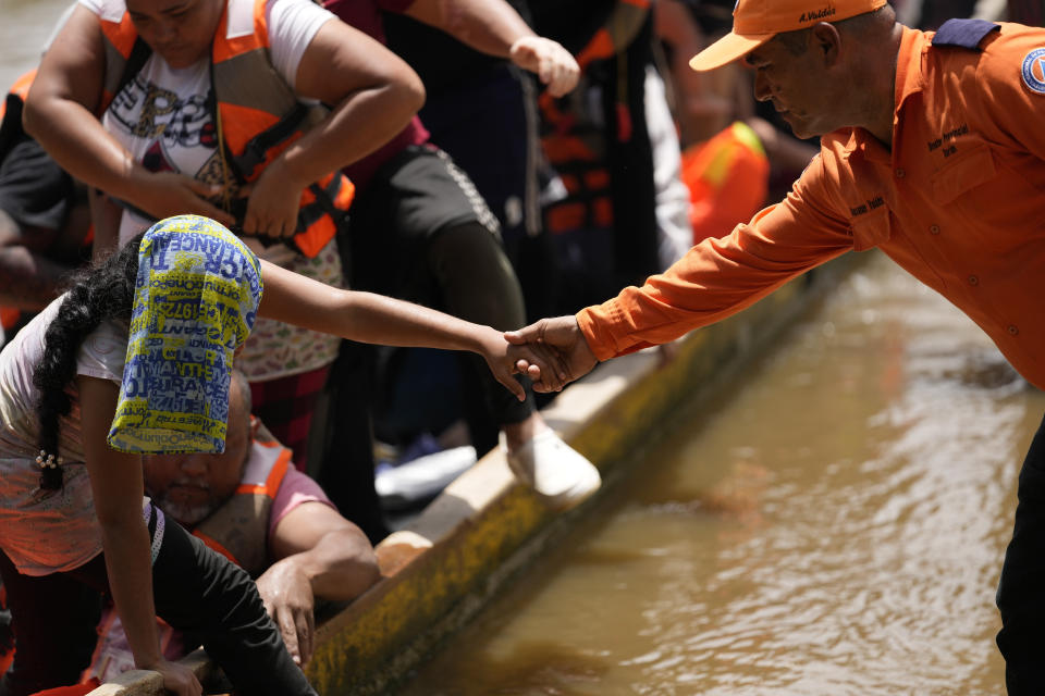 ARCHIVO - Un funcionario de protección civil ayuda a los migrantes a bajar de un barco en Lajas Blancas, Panamá, el viernes 28 de junio de 2024, después de que los migrantes cruzaron a pie el Tapón del Darién desde Colombia. (AP Foto/Matías Delacroix, Archivo)