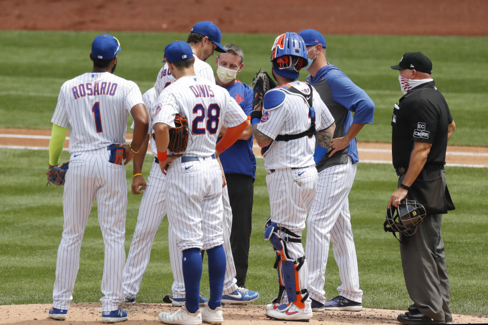 A trainer visits New York Mets starting pitcher Jacob deGrom, third from left, on the mound during the first inning of a baseball game against the Miami Marlins at Citi Field, Sunday, Aug. 9, 2020, in New York. (AP Photo/Kathy Willens)