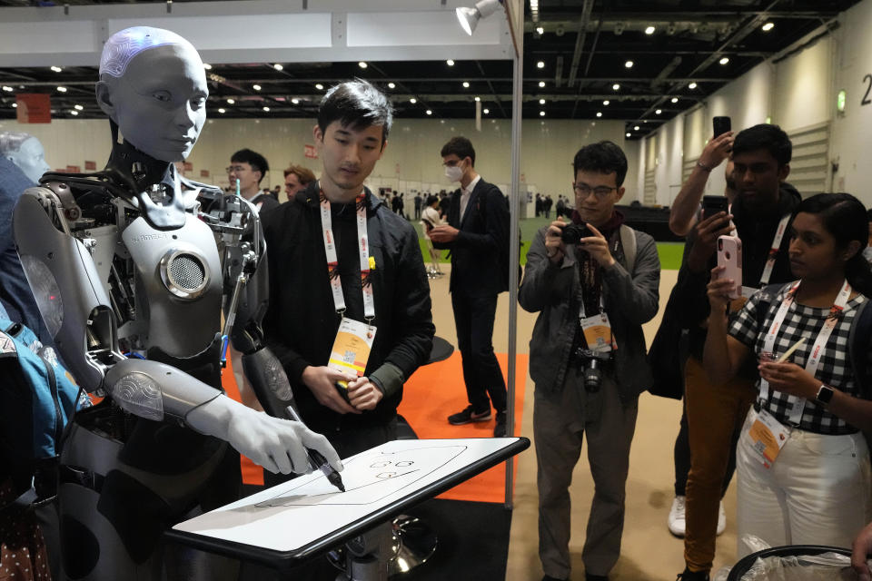 A robot designed by Engineers Arts and called AMECA, interacts with visitors during the International Conference on Robotics and Automation ICRA in London, Tuesday, May 30, 2023. The 2023 ICRA brings together the world's top academics, researchers, and industry representatives to show the newest developments. Ameca is a humanoid robot platform for human-robot interaction. (AP Photo/Frank Augstein)