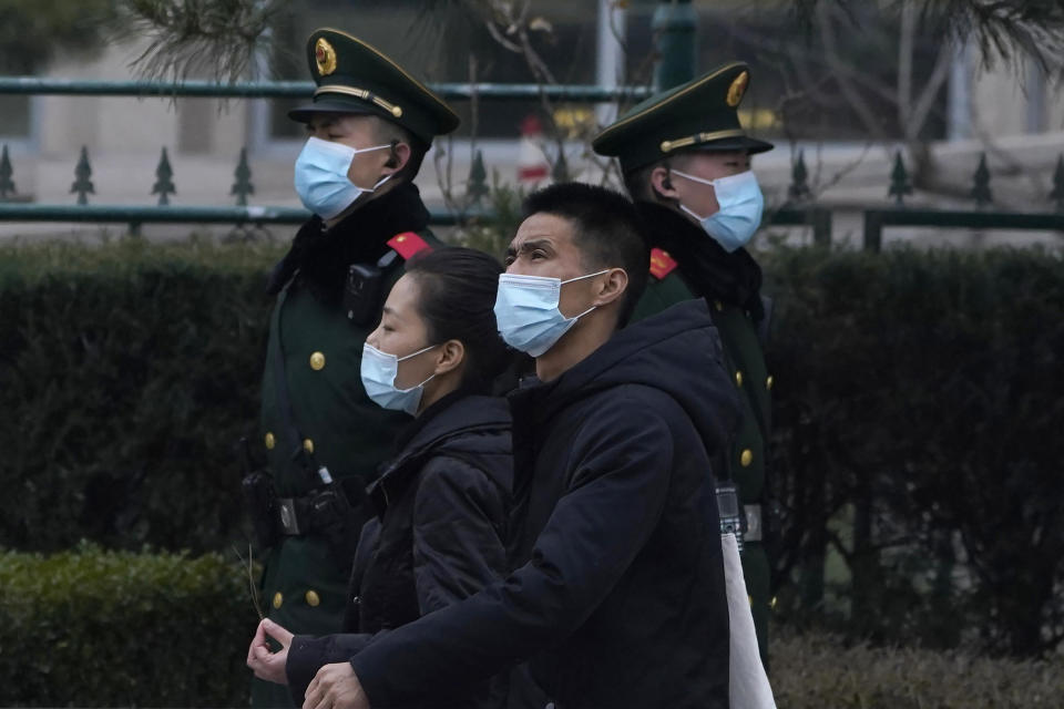 Residents wearing masks past by paramilitary officers on duty near the Great Hall of the People where delegates are attending the opening session of the Chinese People's Political Consultative Conference (CPPCC) held in Beijing on Thursday, March 4, 2021. (AP Photo/Ng Han Guan)