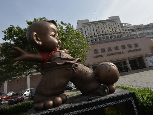 Una estatua de un niño jugando al juego de pelota tradicional chino 'Cuju' es fotografiada a la entrada del Museo del Fútbol Linzi en la ciudad de Zibo, China, el 15 de mayo de 2014 (AFP/Archivos | Mark Ralston)