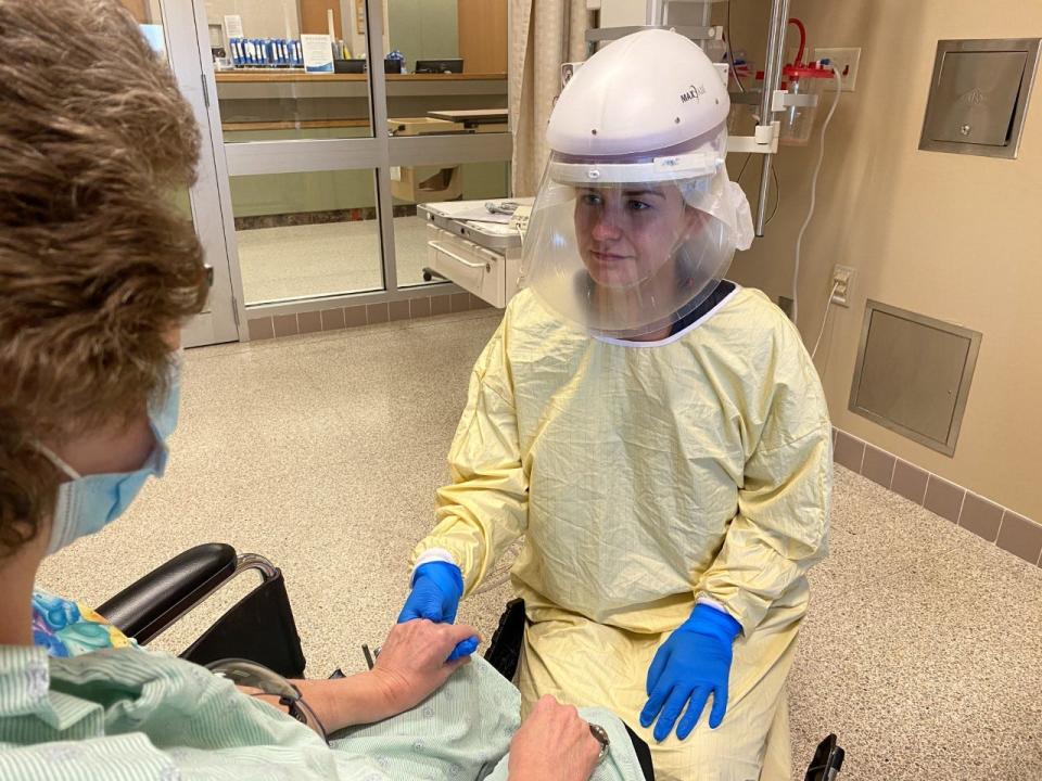 Samantha Pitts, a nurse in the critical care unit at HSHS Sacred Heart Hospital in Eau Claire, with a patient. Pitts is wearing personal protective equipment, including battery-powered device known as a powered air-purifying respirator, or PAPR.