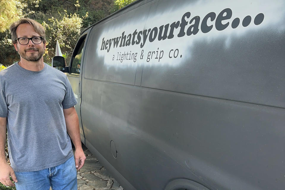 Ryan Meyer poses next to his company vehicle in Los Angeles on Sept. 14, 2023. Meyer is an entertainment industry lighting specialist who is among thousands of workers forced to take most any job they can get to stay afloat during the prolonged Hollywood strikes. (Ryan Meyer via AP)