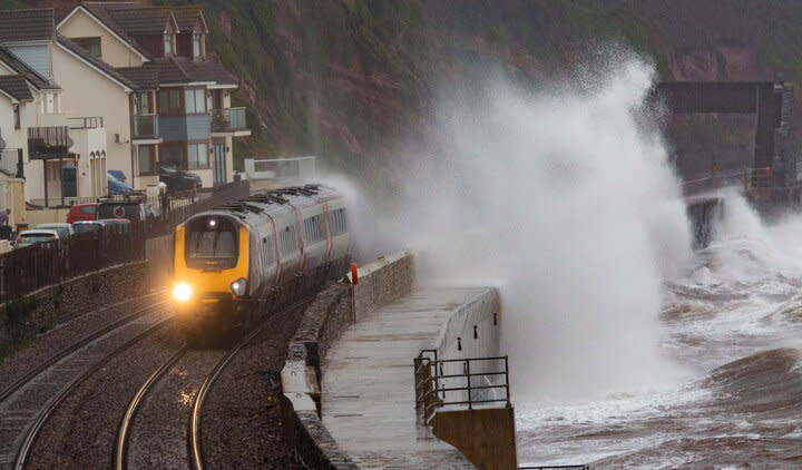 A train passes the Dawlish seafront, Devon, during high winds.