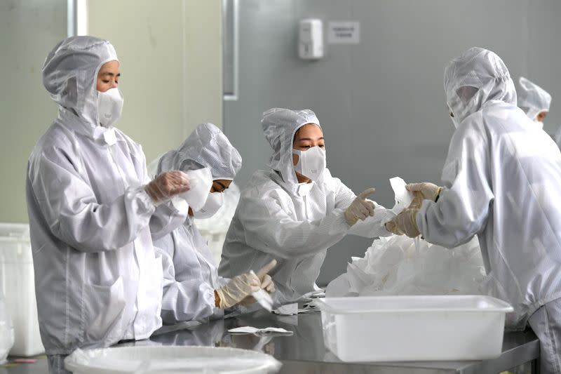 FILE PHOTO: Employees work on a production line manufacturing face masks at a factory, as the country is hit by an outbreak of the novel coronavirus, in Fuzhou