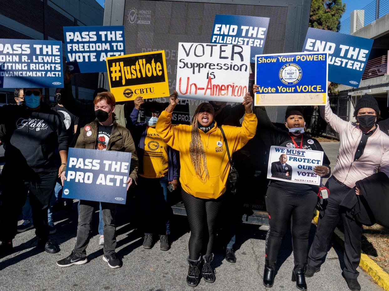 Demonstrators wave signs advocating for voting rights in Atlanta, Georgia, before President Biden and Vice President Harris speak.