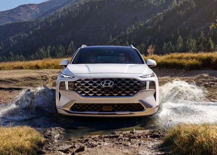 2021 white Hyundai Santa Fe driving through water with mountains in background