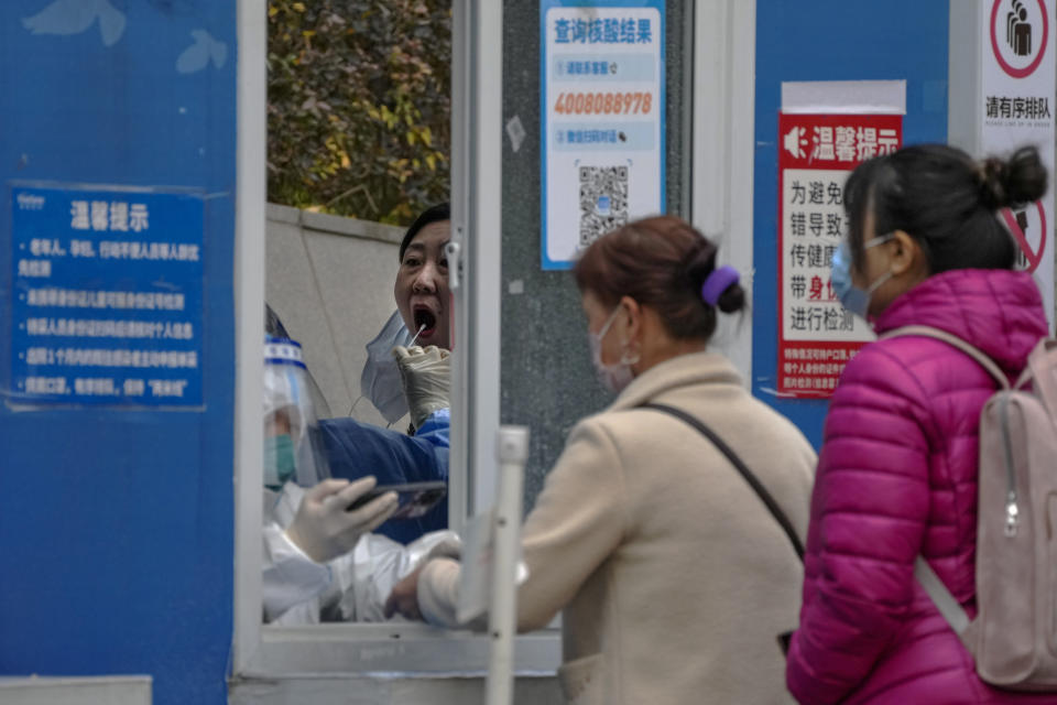 Residents wearing face masks line up to register to have their throat swabbed for a COVID-19 test at a coronavirus testing site in Beijing, Tuesday, Nov. 22, 2022. Anti-virus controls that are confining millions of Chinese families to their homes and shut shops and offices are spurring fears already weak global business and trade might suffer. (AP Photo/Andy Wong)