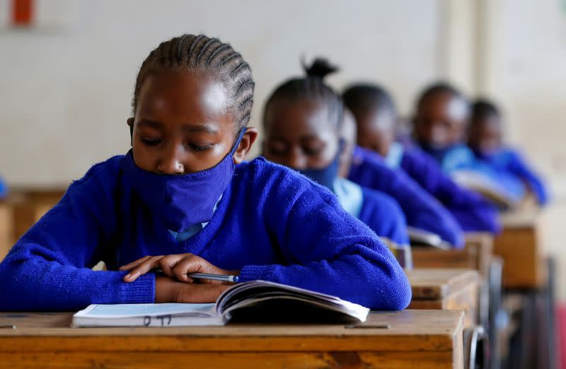 A schoolgirl wears a face mask as she reads a book inside a classroom at the Olympic Primary School during the partial reopening of schools, in Nairobi