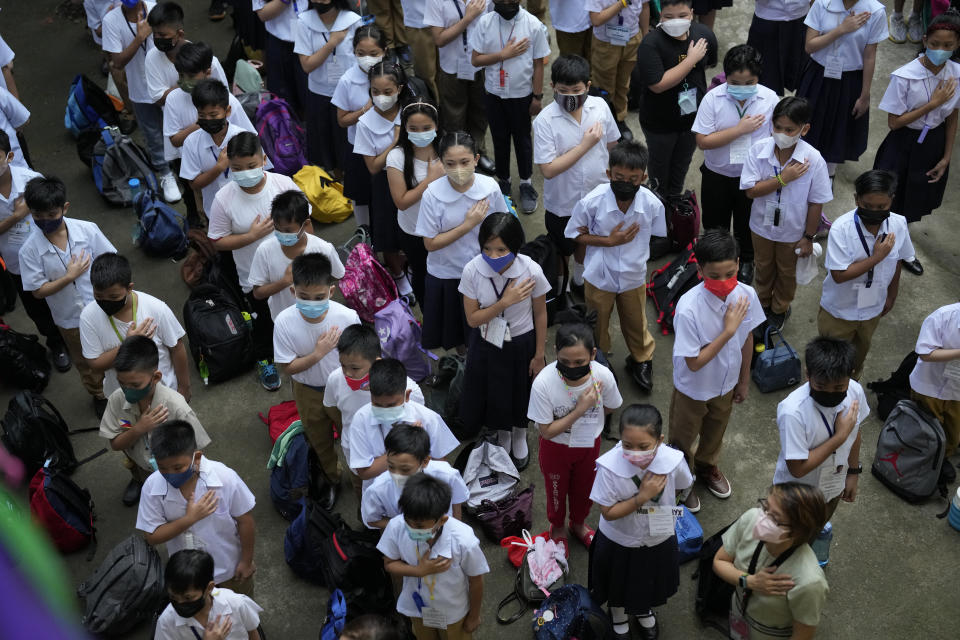 Students attend a flag raising ceremony during the opening of classes at the San Juan Elementary School in metro Manila, Philippines on Monday, Aug. 22, 2022. Millions of students wearing face masks streamed back to grade and high schools across the Philippines Monday in their first in-person classes after two years of coronavirus lockdowns that are feared to have worsened one of the world's most alarming illiteracy rates among children. (AP Photo/Aaron Favila)