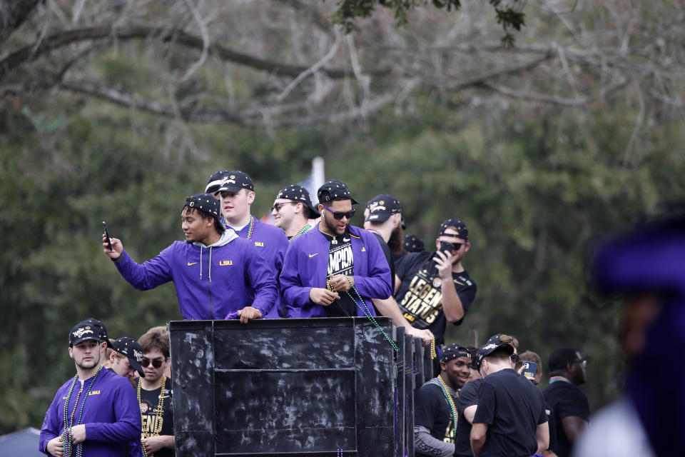 LSU players toss beads and ride on floats during a parade celebrating their NCAA college football championship, Saturday, Jan. 18, 2020, on the LSU campus in Baton Rouge, La. (AP Photo/Gerald Herbert)