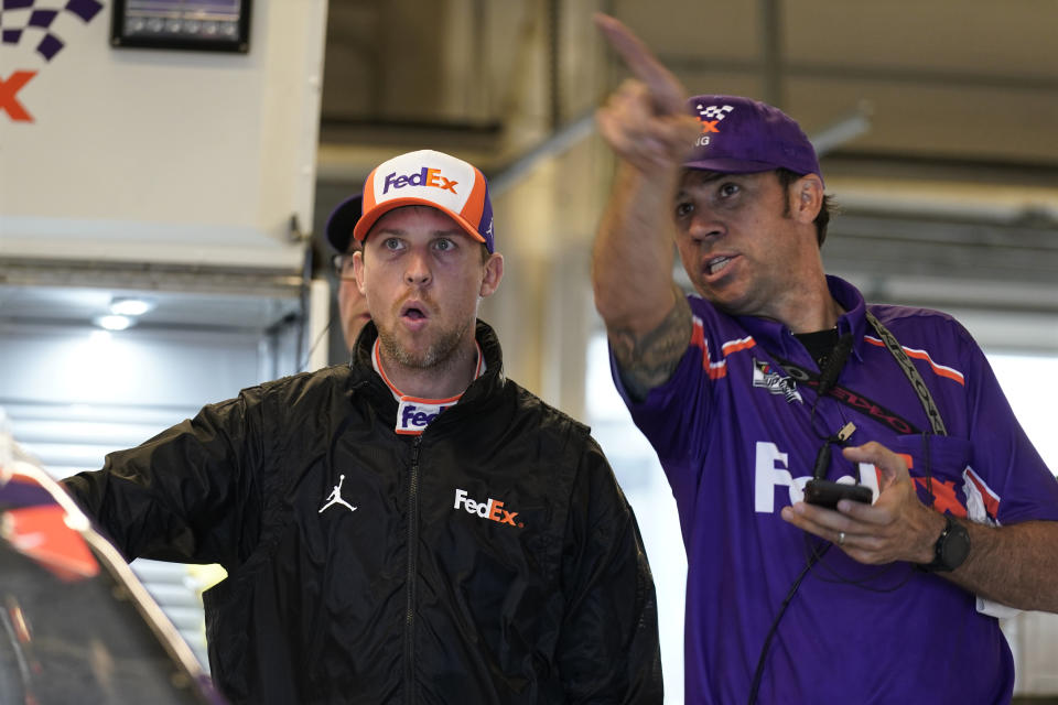 Denny Hamlin, left, talks to a crew member before practice for Sunday's NASCAR Cup Series auto race at the Circuit of the Americas in Austin, Texas, Saturday, May 22, 2021. (AP Photo/Chuck Burton)