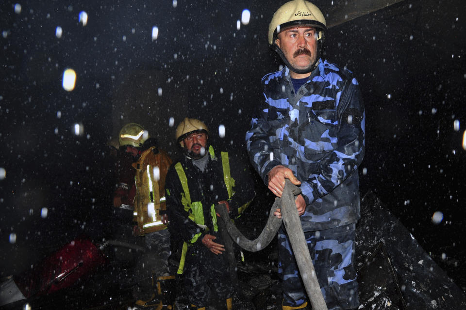 This photo released by the Syrian official news agency SANA, shows firefighters working at the scene of a fire that broke out in the La Mirada Mall building, in Damascus, Syria, Tuesday, March 1, 2022. SANA said 11 people died and seven others were injured. (SANA via AP)