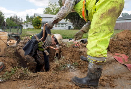 Teichert Construction plumber Victor De Anda (L) and laborer Israel Moreo install a water meter on 21st Street during the city's water meter retrofitting program in Sacramento, April 8, 2015. REUTERS/James Glover III