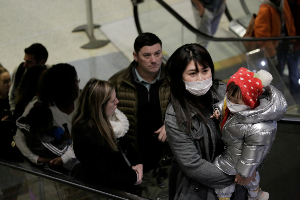 Travellers wearing masks arrive on a direct flight from China at Seattle-Tacoma International Airport