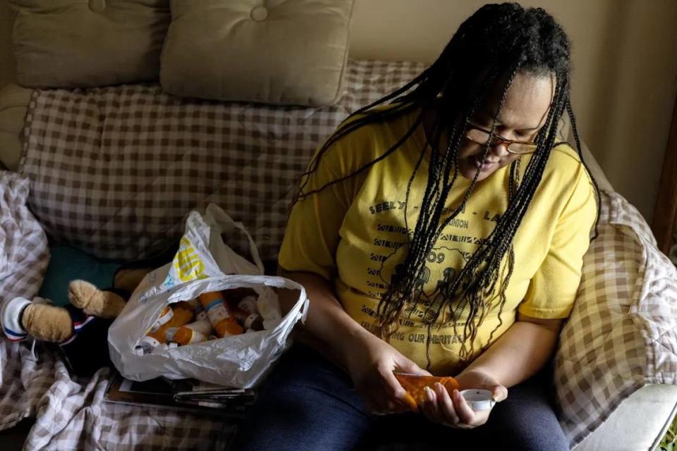 Selinda Walker, 47, takes one of several medications at her mom’s home in Columbus. Selinda has an autoimmune disease called Graves’ Disease.