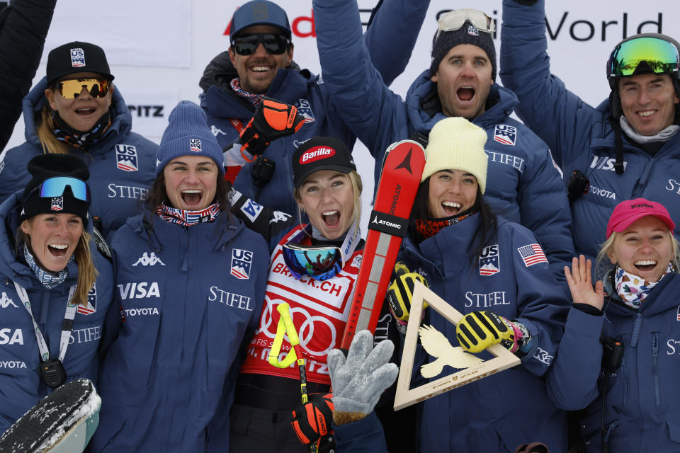 United States' Mikaela Shiffrin, center, celebrates on the podium with the team after winning an alpine ski, women's World Cup downhill race, in St. Moritz, Switzerland, Saturday, Dec.9, 2023. (AP Photo/Alessandro Trovati)