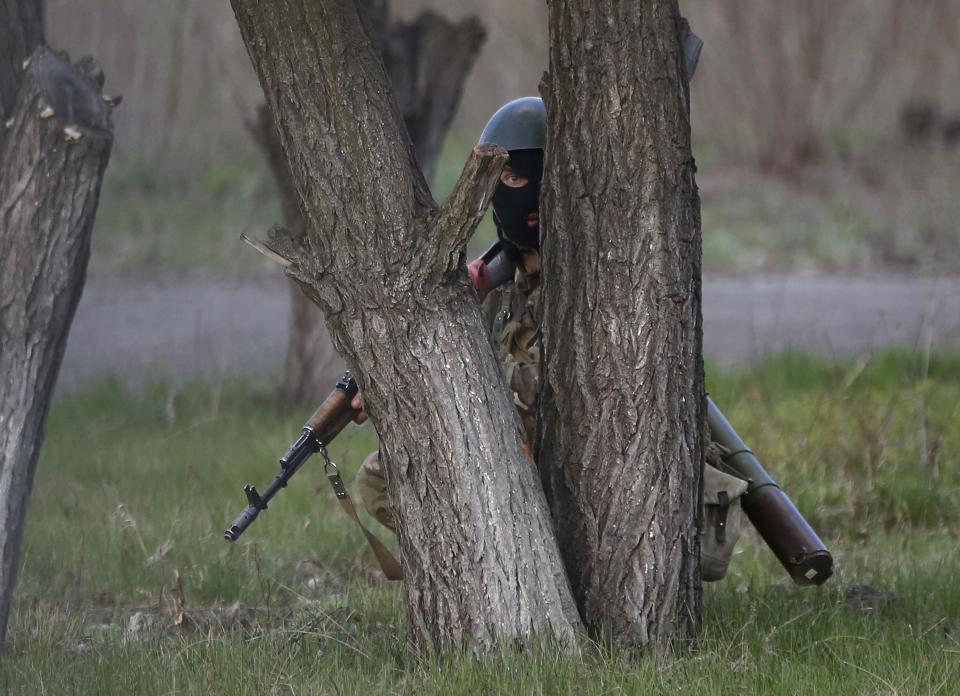 An Ukrainian soldier takes cover behind a tree as pro-Russia protesters gathered in front of a Ukrainian airbase in Kramatorsk, in eastern Ukraine April 15, 2014. Ukrainian armed forces on Tuesday launched a "special operation" against militiamen in the country's Russian speaking east, authorities said, recapturing a military airfield from pro-Moscow separatists. REUTERS/Marko Djurica (UKRAINE - Tags: POLITICS CIVIL UNREST MILITARY TPX IMAGES OF THE DAY)