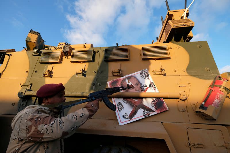 FILE PHOTO: A member of Libyan National Army (LNA) commanded by Khalifa Haftar, points his gun to the image of Turkish President Tayyip Erdogan hanged on a Turkish military armored vehicle, which LNA said they confiscated during Tripoli clashes, in Benghaz