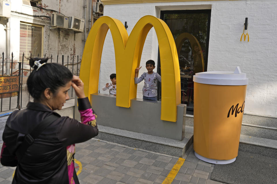A woman takes photograph her children outside McDonald's outlet, in New Delhi, India, Friday, March 15, 2024. System failures at McDonald’s were reported worldwide Friday, shuttering some restaurants for hours and leading to social media complaints from customers, in what the fast food chain called a “technology outage” that was being fixed. (AP Photo/Manish Swarup)