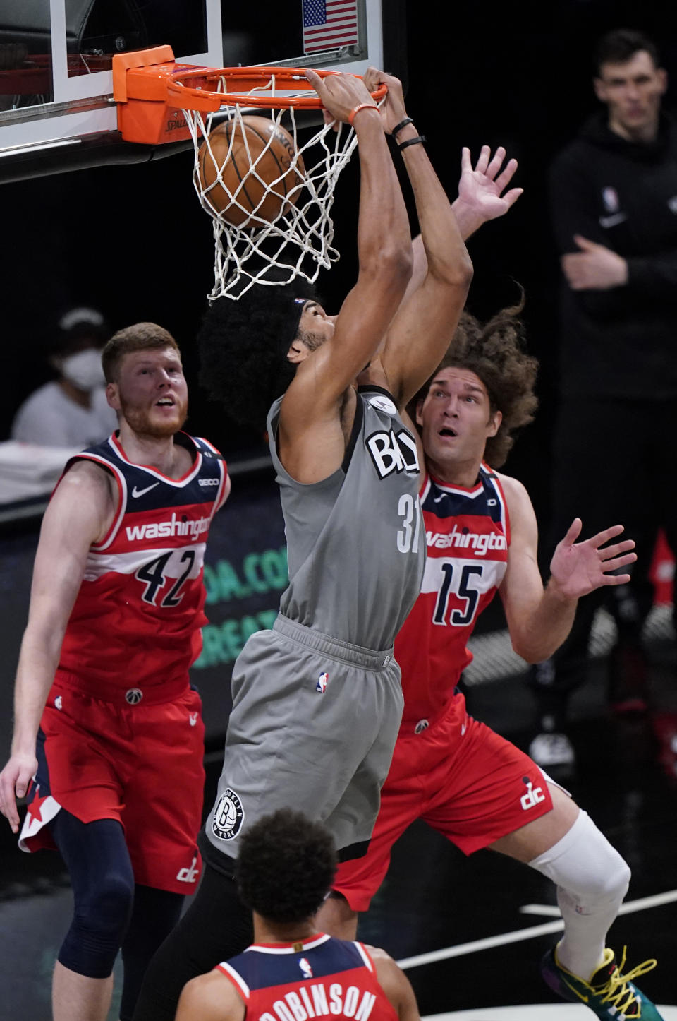 Brooklyn Nets center Jarrett Allen, center, executes a backward dunk with Washington Wizards Davis Bertans, left, and Robin Lopez, right, defending during the second quarter of an NBA basketball game, Sunday, Jan. 3, 2021, in New York. (AP Photo/Kathy Willens)