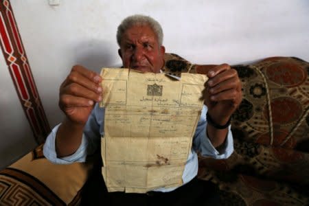 Palestinian Ahmed Jarghoun, 75, displays a land registration certificate from the British era, in Khan Younis in the southern Gaza Strip June 18, 2018. REUTERS/Ibraheem Abu Mustafa