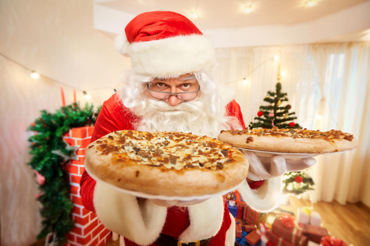 Pizza in the hands of Santa Claus at Christmas, happy new year close-up.