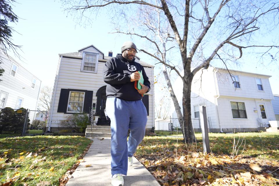 William Olivier, a community impact pastor with the nonprofit Bridge Builders, goes door to door Nov. 9 in Milwaukee distributing flyers about an upcoming meeting.