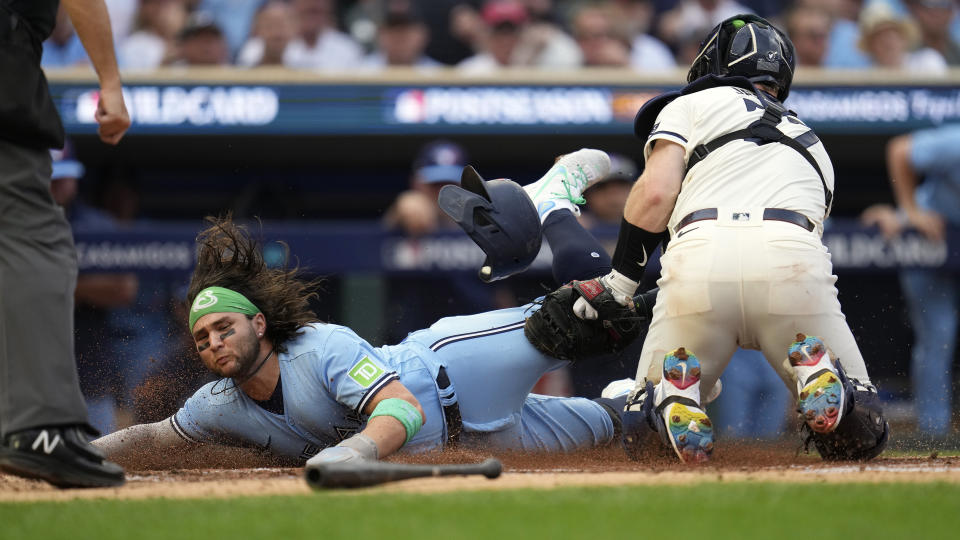 Toronto Blue Jays' Bo Bichette, left, is tagged out at home plate by Minnesota Twins catcher Ryan Jeffers after an infield single by Kevin Kiermaier during the fourth inning in Game 1 of an AL wild-card baseball playoff series Tuesday, Oct. 3, 2023, in Minneapolis. (AP Photo/Abbie Parr)
