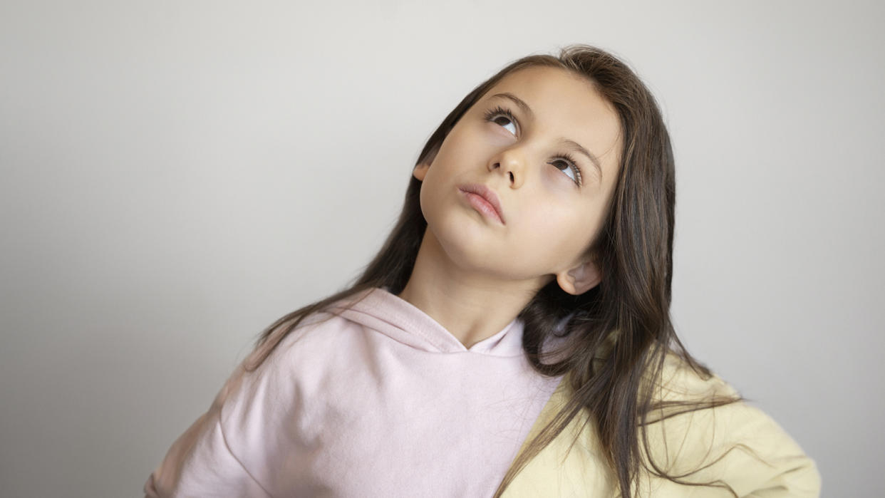 Young girl with long brown hair, looking up in deep thought