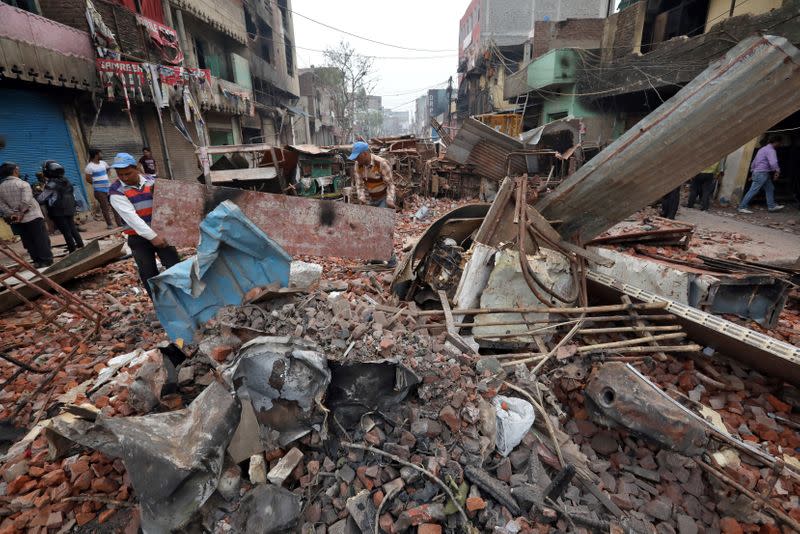 Men remove debris in a riot affected area following clashes between people demonstrating for and against a new citizenship law in New Delhi