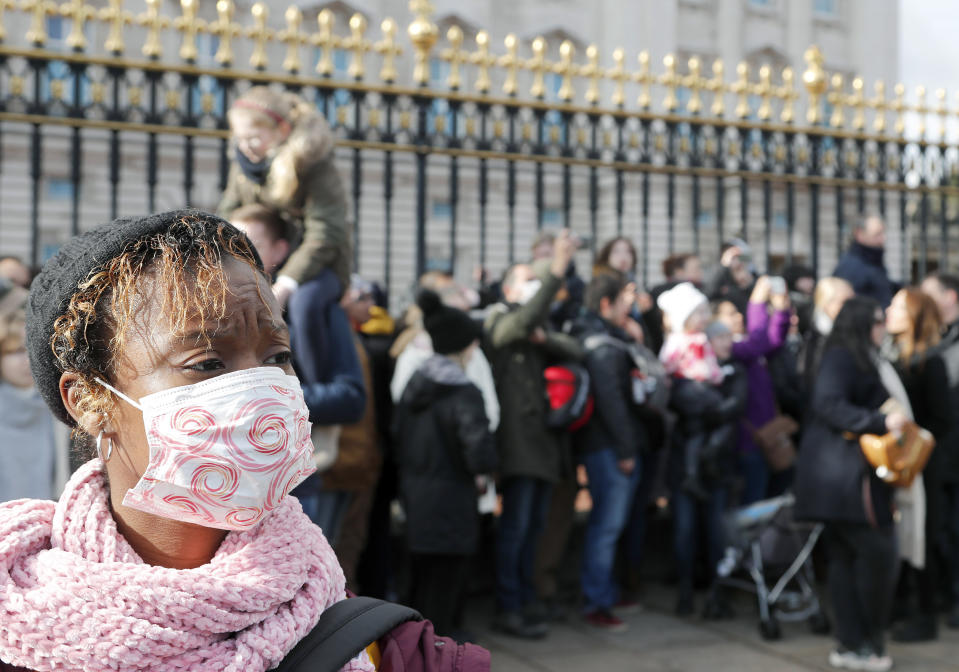 A tourist wears a face mask as she watches the Changing of the Guard, at Buckingham Palace, in London, Monday, March 2, 2020. British Prime Minister Boris Johnson told reporters Sunday at a health center in London that he was “very, very confident” that Britain’s National Health Service can cope with the coronavirus outbreak. (AP Photo/Frank Augstein)